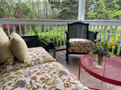 a porch with two chairs and a table with a vase of flowers at Beaver Valley Farmhouse with Pool & Stunning Views in Kimberley