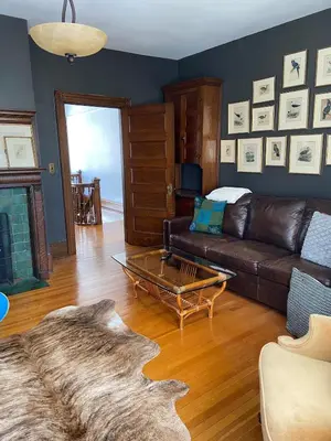 a living room with a leather couch and a table at Warm, Stylish Edwardian Escape in Downtown Meaford in Meaford