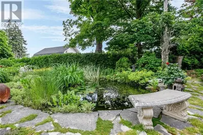 a stone bench in a garden with a pond at Warm, Stylish Edwardian Escape in Downtown Meaford in Meaford