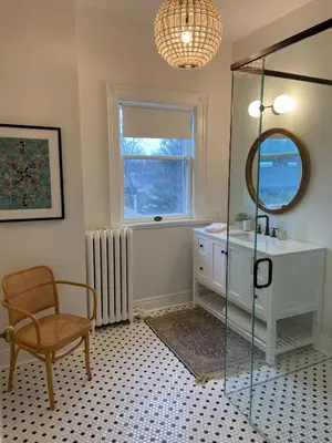 a bathroom with a shower and a sink and a chair at Warm, Stylish Edwardian Escape in Downtown Meaford in Meaford