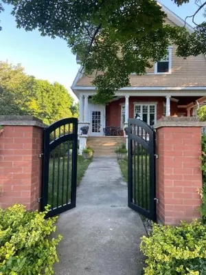 a gate in front of a house with a driveway at Warm, Stylish Edwardian Escape in Downtown Meaford in Meaford