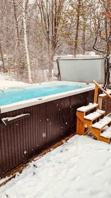 a wooden bench sitting next to a swimming pool in the snow at Rice Lake Retreat 2 Bed Home 16 Ft Swim spa Sauna in Bailieboro