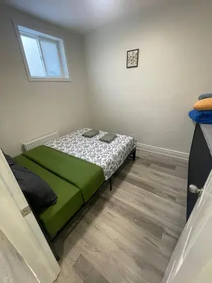 a bedroom with a bed with green sheets and a window at DOWNTOWN-BMO Field Stay-Next to Transit-Restaurants-Union Station in Toronto