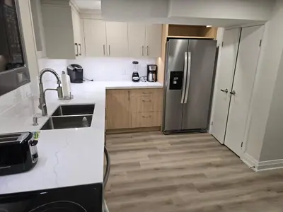 a kitchen with white cabinets and a stainless steel refrigerator at Charming Streetsville 2 Bedroom Suite with Parking and Laundry in Mississauga