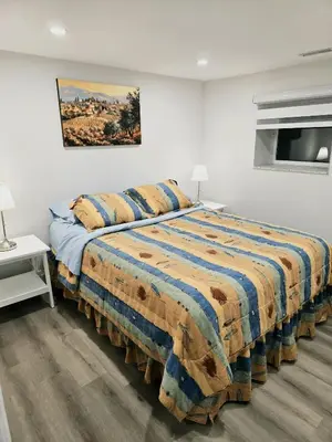a bedroom with a large bed in a white room at Charming Streetsville 2 Bedroom Suite with Parking and Laundry in Mississauga