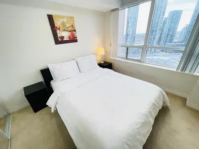 a bedroom with a large white bed with a window at 2 Bedroom Luxury Suite Across Square One in Mississauga