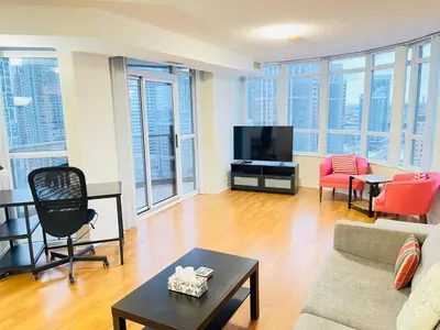 a living room with a couch and a tv at 2 Bedroom Luxury Suite Across Square One in Mississauga