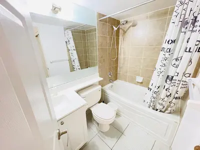 a white bathroom with a toilet and a sink and a tub at 2 Bedroom Luxury Suite Across Square One in Mississauga