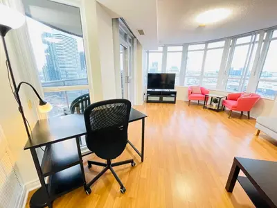 a living room with a desk and chairs and a television at 2 Bedroom Luxury Suite Across Square One in Mississauga