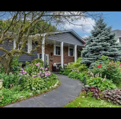 a house with a garden of flowers in front of it at Grimsby Lake Front Home in Grimsby