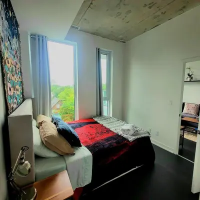 a bedroom with a bed and a large window at Feel at home Spacious Industrial Style, 2bed 2bath in Toronto