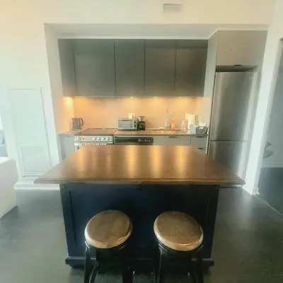 a kitchen with a large wooden island with two stools at Feel at home Spacious Industrial Style, 2bed 2bath in Toronto
