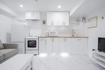a white kitchen with white appliances and a couch at Bright Modern 1BR Suite Kitchen Workspace Smart TV in Bowmanville