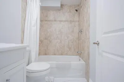 a white bathroom with a toilet and a shower at Bright Modern 1BR Suite Kitchen Workspace Smart TV in Bowmanville