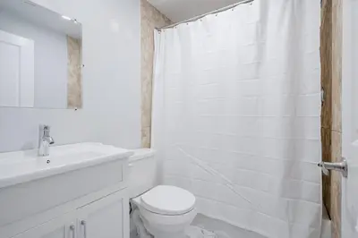 a white bathroom with a toilet and a sink at Bright Modern 1BR Suite Kitchen Workspace Smart TV in Bowmanville