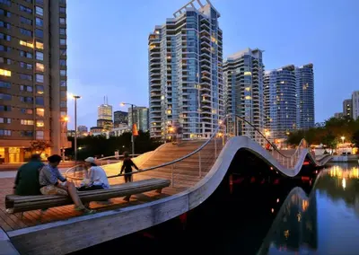 two people sitting on a bench next to a bridge at Lux Harbourfront Home Sleeps 10 with Free Parking in Toronto