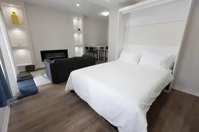 a bedroom with a white bed and a living room at Cozy Cove Retreat, Private Suite Near Friday Harbour, Barrie & Lake Simcoe in Innisfil