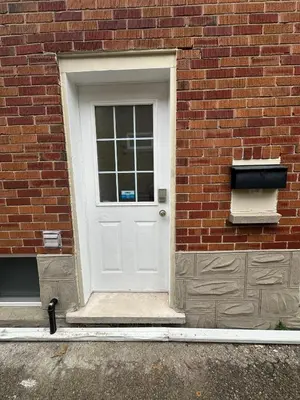 a white door on the side of a brick building at Modern 2 bedrooms 1 bath updated unit Near Downtown Kitchener & Airport in Kitchener