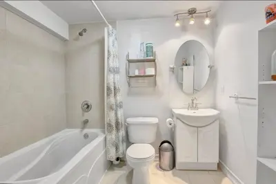 a white bathroom with a tub and a toilet and a sink at A very peaceful home in Oshawa