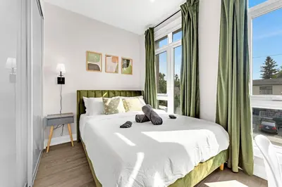 a bedroom with a bed and a large window at Winter Deal! Modern 4BR w/Parking, Prime Location in Toronto