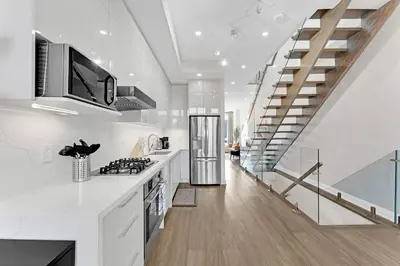 a kitchen with white countertops and a staircase at Winter Deal! Modern 4BR w/Parking, Prime Location in Toronto
