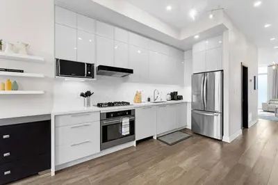 a kitchen with white cabinets and a stainless steel refrigerator at Winter Deal! Modern 4BR w/Parking, Prime Location in Toronto