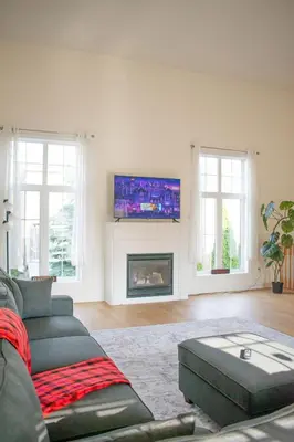 a living room with a couch and a tv above a fireplace at Karibu Home Retreat, 5 min to Ontario Largest Spa in Ajax