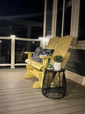 a yellow bench sitting on a porch at night at Prime Waterfront Cottage on Sandbanks Area Resort in Cherry Valley
