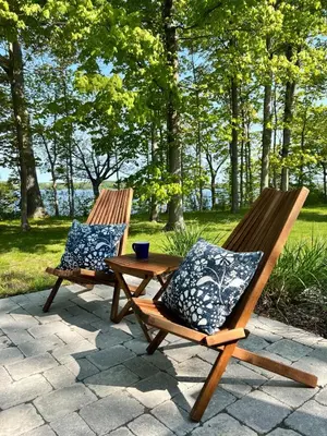 two wooden chairs with pillows sitting next to a table at Prime Waterfront Cottage on Sandbanks Area Resort in Cherry Valley