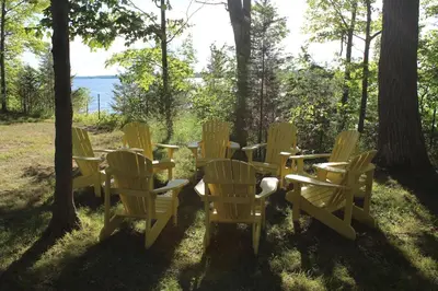 a group of yellow chairs and tables in the grass at Prime Waterfront Cottage on Sandbanks Area Resort in Cherry Valley