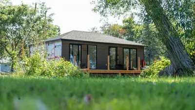 a small house with glass windows in a field at Lakeview Willow Bay Cottages in Harwood in Harwood