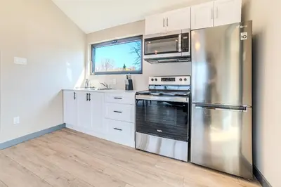 a kitchen with white cabinets and a stainless steel refrigerator at Lakeview Willow Bay Cottages in Harwood in Harwood