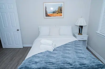 a white bed in a room with a picture on the wall at Cozy Bungalow Near Niagara Falls - Perfect Family Retreat in Niagara Falls
