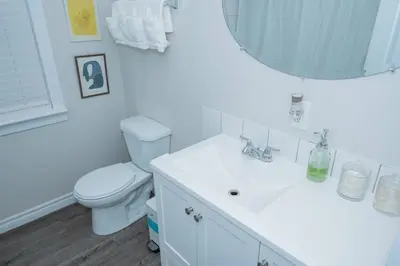 a white bathroom with a toilet and a sink at Cozy Bungalow Near Niagara Falls - Perfect Family Retreat in Niagara Falls