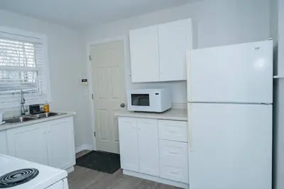 a white kitchen with a refrigerator and a microwave at Cozy Bungalow Near Niagara Falls - Perfect Family Retreat in Niagara Falls