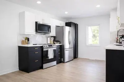 a kitchen with black and white cabinets and a refrigerator at 5 bedrooms for large groups near the falls in Port Colborne