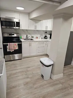 a kitchen with white cabinets and a trash can at Central Signature Stay Downtown-Direct Transit to BMO Field Union & Free Wifi in Toronto