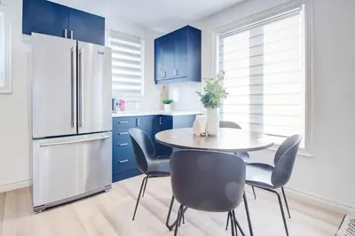 a kitchen with blue cabinets and a table and chairs at Stylish 3BR Steps to Canal, Easy Drive to Falls in Port Colborne