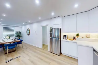 a kitchen and dining room with white cabinets and a table at Lux 7 Bedroom Home [Near Rogers Stadium/Downsview] in Toronto