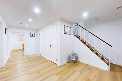 a white hallway with a staircase in a house at Lux 7 Bedroom Home [Near Rogers Stadium/Downsview] in Toronto
