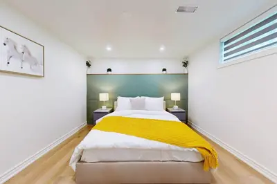 a bedroom with a large bed with yellow blanket at Lux 7 Bedroom Home [Near Rogers Stadium/Downsview] in Toronto