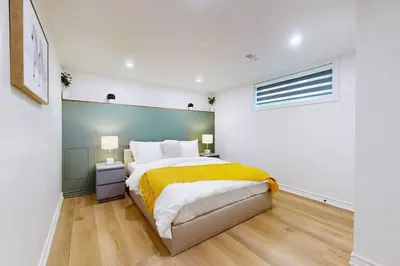 a bedroom with a large bed with a yellow blanket at Lux 7 Bedroom Home [Near Rogers Stadium/Downsview] in Toronto