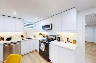 a kitchen with white cabinets and a yellow chair at Lux 7 Bedroom Home [Near Rogers Stadium/Downsview] in Toronto