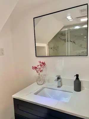 a bathroom sink with a vase of flowers and a mirror at Cozy Private Room with Shared Bathroom in Toronto in Toronto