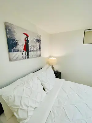 a white bed in a bedroom with a painting on the wall at Cozy Private Room with Shared Bathroom in Toronto in Toronto