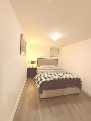 a bedroom with a bed in a white room at Cedar Hedge Private Basement Apartment in Milton