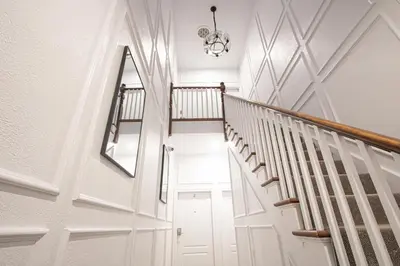 a hallway with white walls and stairs with a mirror at Designer 2BR Suite - Steps to Vic Hospital - Wortley in London