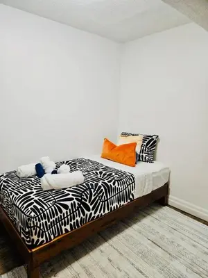 a bedroom with a bed with black and white sheets at Charming 4 Bed Home + 2Parking in Toronto