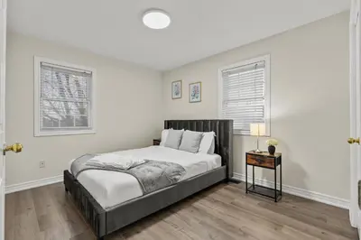 a bedroom with a large bed and two windows at Chelsea Suite 3BR, 1B with parking for 28plus stays in St. Catharines