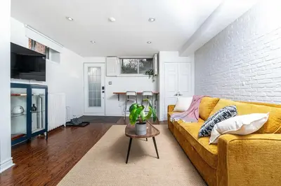 a living room with a yellow couch and a brick wall at Contemporary 1BR Basement Suite with Private Entrance in Toronto